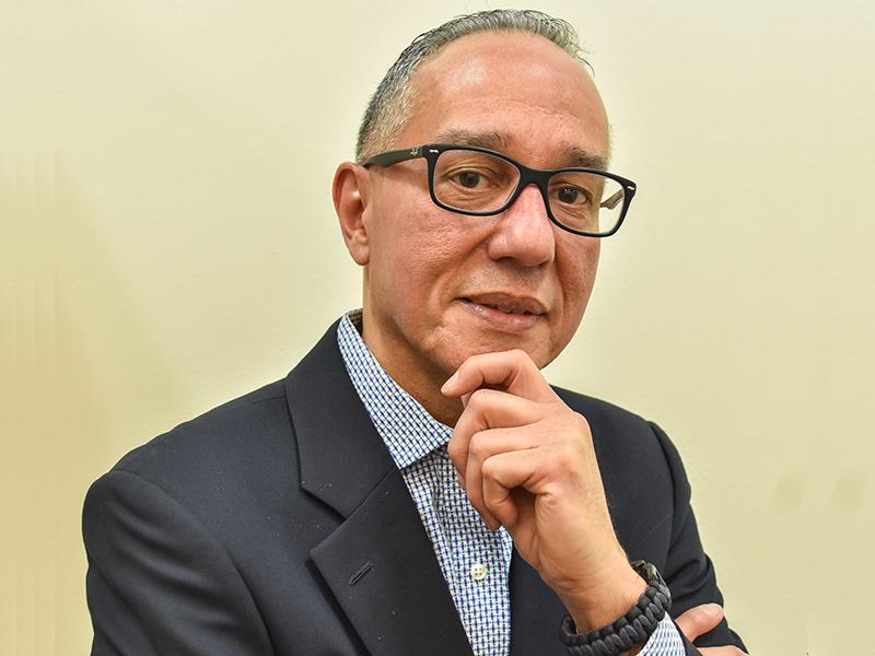 Man in suit looking at camera, with his hand on his chin